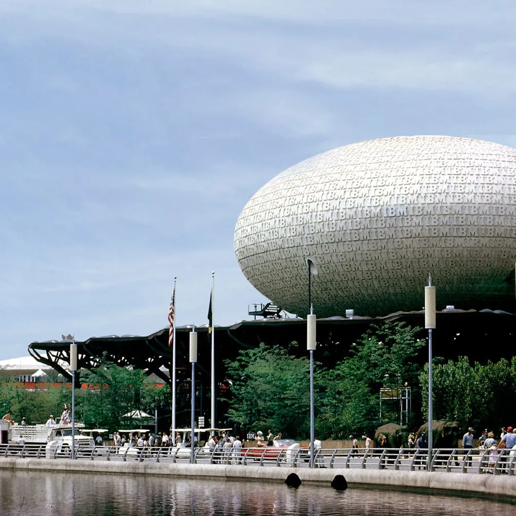 Le pavillon IBM de l’Exposition universelle de New York en 1964 : un grand ovoïde blanc couvert du mot IBM, posé sur une structure arborescente.